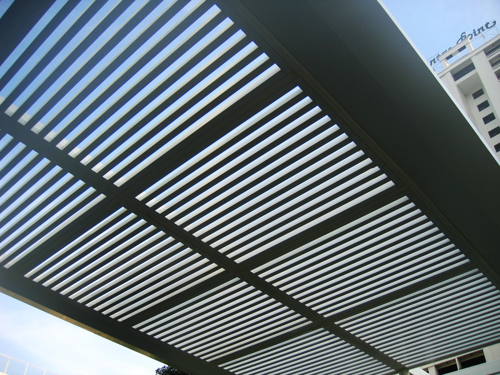 Terrasse extérieure moderne avec pergola contemporaine à structure métallique blanche et toiture plate ornée de tuiles orange-rouge