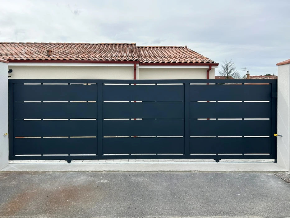 Entrée majestueuse du domaine viticole Clos Vougeot avec portail en fer forgé orné entre deux piliers en pierre calcaire
