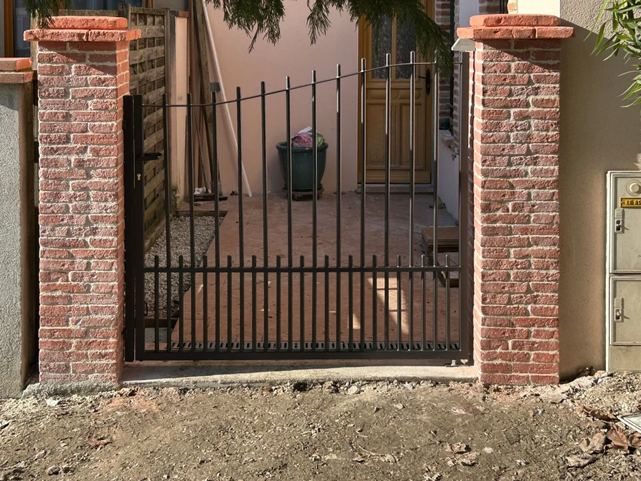 Entrée de propriété rustique au crépuscule avec portail en bois à lames verticales, éclairage d'ambiance chaleureux