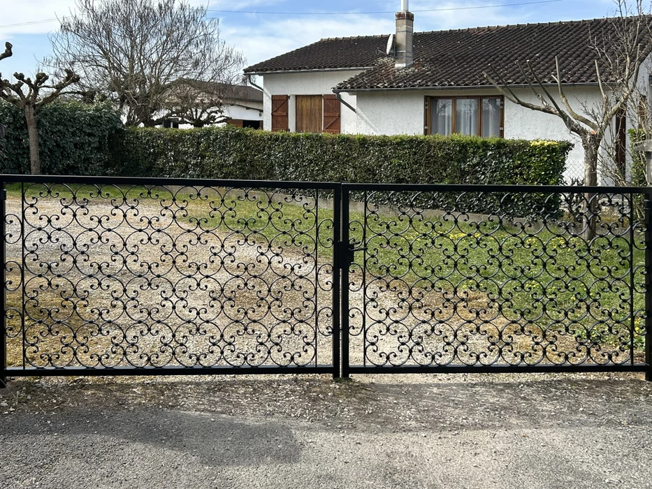 Entrée de propriété résidentielle avec portail en bois blanc partiellement ouvert