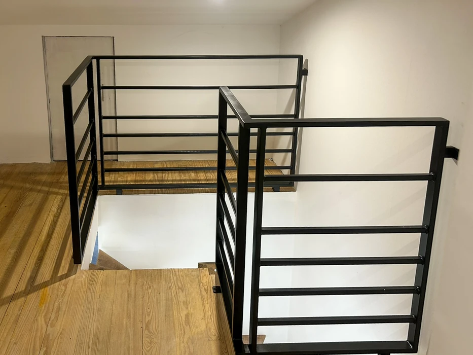 Scène extérieure d'un jardin public avec rambarde ornementale en fer forgé vert foncé longeant une allée