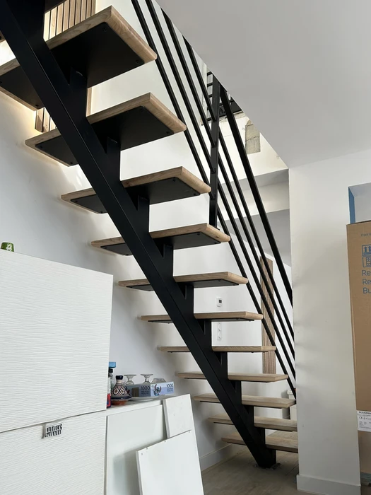 Escalier hélicoïdal métallique dans espace intérieur contemporain aux murs béton brut